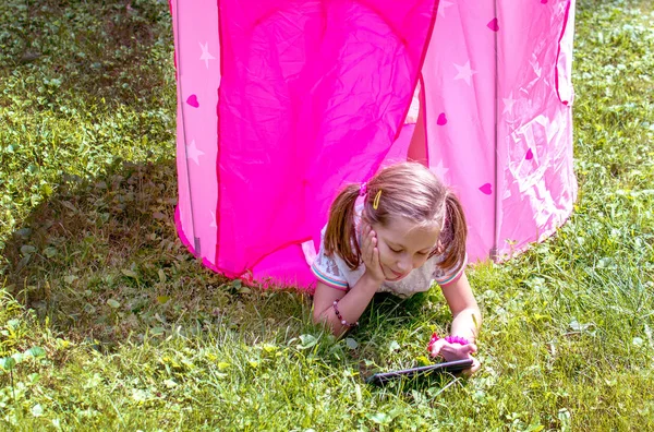 Little girl watching a tablet outside — Stock Photo, Image