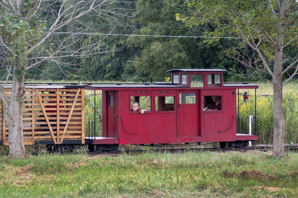 Küçük çocuk kırmızı bir caboose tren vagonunun penceresinden dışarı bakar — Stok fotoğraf