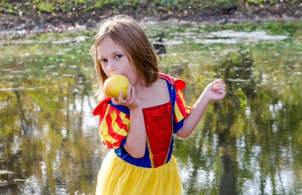 Mladá dívka jí jablko ve své princezně Halloweenské kostýmu — Stock fotografie