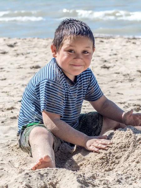 Menino feliz brincando na areia na praia — Fotografia de Stock