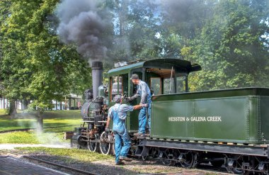 Hesston Indiana Usa, 15 Eylül 2019. Tulumlu ve şapkalı iki adam, Hesston Tren Müzesi 'nde aileleri ziyaret etmeye hazır antika bir buhar makinesinin yanında duruyorlar.