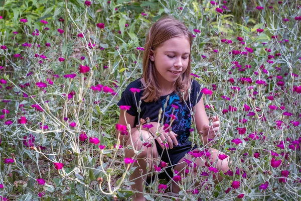 Młoda dziewczyna siedzi na polu dzikich kwiatów — Zdjęcie stockowe