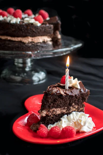 Tranche de gâteau d'anniversaire avec une bougie allumée — Photo