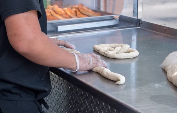 Worker making pretzels at a fair — Stock Photo, Image