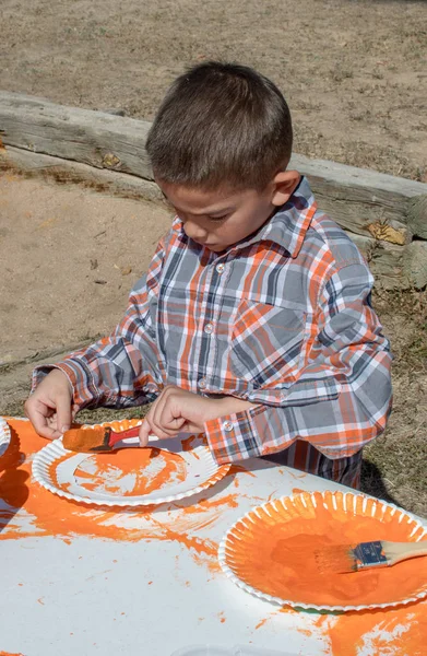 Cute young boy paints a Fall pumpkin — Stock Photo, Image