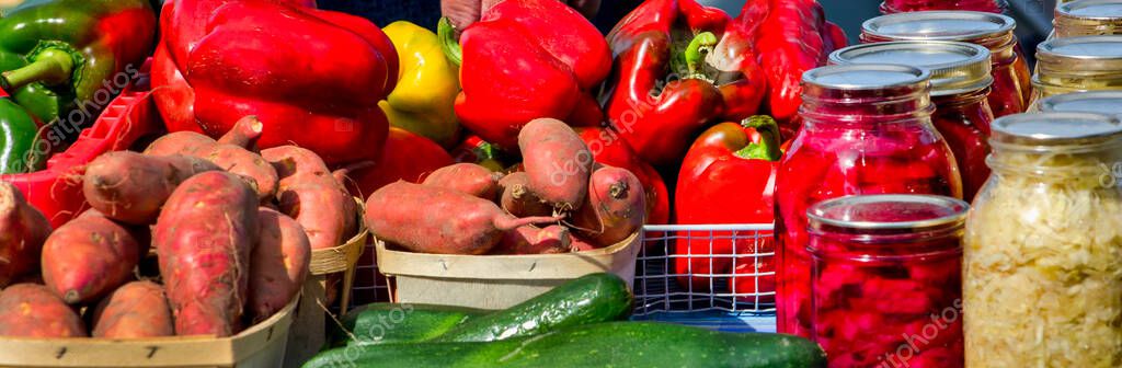 Fresh healthy foods for sale at a farm stand include red and green peppers, sweet potatoes, cucumbers, and jars of beets and sauerkraut — Stock Image Fresh Healthy Foods Sale Farm Stand Include Red Green Peppers Royalty Free Stock Images
