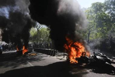 İtfaiyeciler Paris'te Emmanuel Macron politikasına karşı Sarı yelek hareketi tarafından çağrılan bir gösteri sırasında bir sokakta yanan scooter üzerine su püskürtmek, Fransa Nisan'da 20, 2019