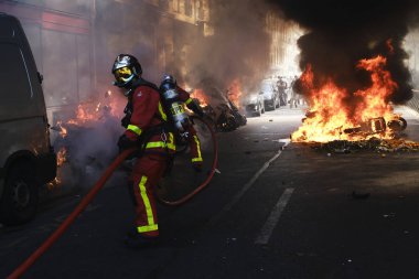 İtfaiyeciler Paris'te Emmanuel Macron politikasına karşı Sarı yelek hareketi tarafından çağrılan bir gösteri sırasında bir sokakta yanan scooter üzerine su püskürtmek, Fransa Nisan'da 20, 2019