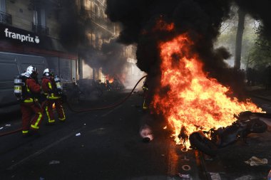 İtfaiyeciler Paris'te Emmanuel Macron politikasına karşı Sarı yelek hareketi tarafından çağrılan bir gösteri sırasında bir sokakta yanan scooter üzerine su püskürtmek, Fransa Nisan'da 20, 2019