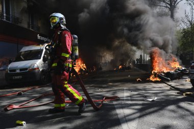 İtfaiyeciler Paris'te Emmanuel Macron politikasına karşı Sarı yelek hareketi tarafından çağrılan bir gösteri sırasında bir sokakta yanan scooter üzerine su püskürtmek, Fransa Nisan'da 20, 2019