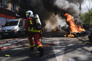 İtfaiyeciler Paris'te Emmanuel Macron politikasına karşı Sarı yelek hareketi tarafından çağrılan bir gösteri sırasında bir sokakta yanan scooter üzerine su püskürtmek, Fransa Nisan'da 20, 2019