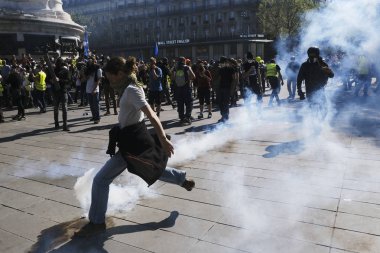 French riot police clash with French yellow vests protesters during a demonstration called by the Yellow vest movement against the policy of Emmanuel Macron  in Paris, France on Apr. 20, 2019 clipart