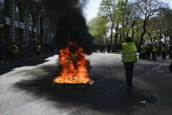 消防士は 2019年4月20日にフランスのパリでエマニュエル マクロンの政策に反対するイエローベスト運動によって呼び出されたデモの間 路上で燃えているスクーターに水を吹きかけました — ストック写真