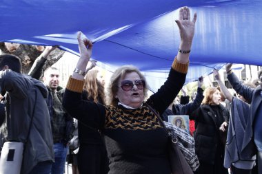 Protestocu bir miting sırasında bir Yunan bayrağı ve dini bir simge tutun 