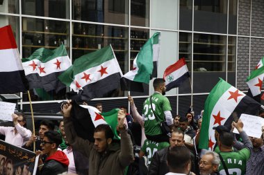 8 Eylül 2018'de Belçika'nın başkenti Brüksel'de Suriye Devlet Başkanı Beşar Esad'a karşı düzenlenen protestoda suriye bayrakları sallayıp slogan atan insanlar.