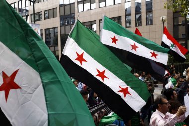 8 Eylül 2018'de Belçika'nın başkenti Brüksel'de Suriye Devlet Başkanı Beşar Esad'a karşı düzenlenen protestoda suriye bayrakları sallayıp slogan atan insanlar.