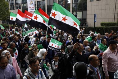 8 Eylül 2018'de Belçika'nın başkenti Brüksel'de Suriye Devlet Başkanı Beşar Esad'a karşı düzenlenen protestoda suriye bayrakları sallayıp slogan atan insanlar.