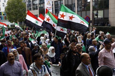 8 Eylül 2018'de Belçika'nın başkenti Brüksel'de Suriye Devlet Başkanı Beşar Esad'a karşı düzenlenen protestoda suriye bayrakları sallayıp slogan atan insanlar.