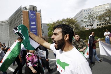 8 Eylül 2018'de Belçika'nın başkenti Brüksel'de Suriye Devlet Başkanı Beşar Esad'a karşı düzenlenen protestoda suriye bayrakları sallayıp slogan atan insanlar.