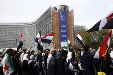 8 Eylül 2018'de Belçika'nın başkenti Brüksel'de Suriye Devlet Başkanı Beşar Esad'a karşı düzenlenen protestoda suriye bayrakları sallayıp slogan atan insanlar.