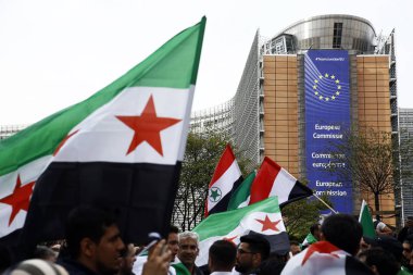 8 Eylül 2018'de Belçika'nın başkenti Brüksel'de Suriye Devlet Başkanı Beşar Esad'a karşı düzenlenen protestoda suriye bayrakları sallayıp slogan atan insanlar.