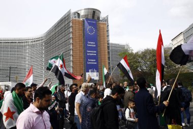 8 Eylül 2018'de Belçika'nın başkenti Brüksel'de Suriye Devlet Başkanı Beşar Esad'a karşı düzenlenen protestoda suriye bayrakları sallayıp slogan atan insanlar.