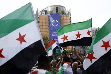 8 Eylül 2018'de Belçika'nın başkenti Brüksel'de Suriye Devlet Başkanı Beşar Esad'a karşı düzenlenen protestoda suriye bayrakları sallayıp slogan atan insanlar.