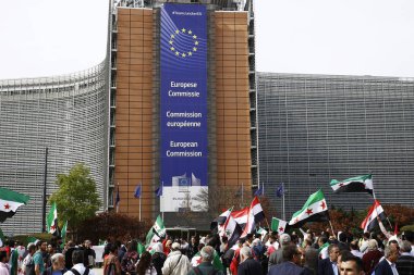 8 Eylül 2018'de Belçika'nın başkenti Brüksel'de Suriye Devlet Başkanı Beşar Esad'a karşı düzenlenen protestoda suriye bayrakları sallayıp slogan atan insanlar.