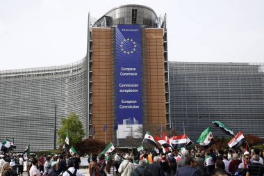 8 Eylül 2018'de Belçika'nın başkenti Brüksel'de Suriye Devlet Başkanı Beşar Esad'a karşı düzenlenen protestoda suriye bayrakları sallayıp slogan atan insanlar.