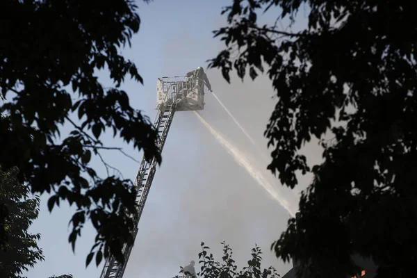 Tűzoltók próbálja eloltani a tüzet, hogy kitört egy épít — Stock Fotó