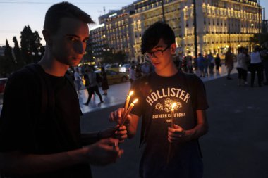 İnsanlar Yunan parliame önünde bir mum ışığı nöbeti katılmak