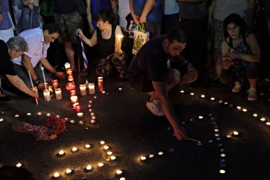 İnsanlar Yunan parliame önünde bir mum ışığı nöbeti katılmak