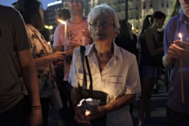İnsanlar Yunan parliame önünde bir mum ışığı nöbeti katılmak