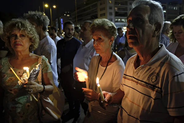 İnsanlar Yunan parliame önünde bir mum ışığı nöbeti katılmak