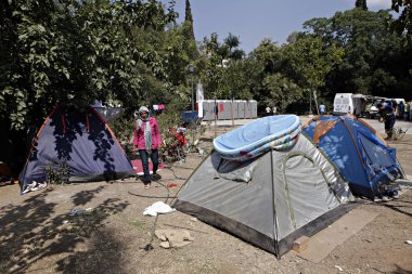 Refugees and migrants in a makeshift camp at Pedion tou Areos park where some 1500 migrants and refugees live in a makeshift camps in Athens, Greece on Aug. 9, 2015 clipart