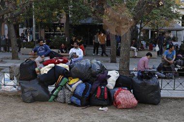 Göçmenler, 13 Kasım 2015, Atina 'nın merkezindeki Victoria meydanında, yüzlerce göçmen ve mültecinin geçici olarak kalabileceği bir yerde oturuyor.