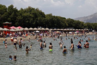 İnsanlar Temmuz ayında Atina Yunanistan 'ın kuzeydoğu banliyölerinde plajları güneşli hava tadını çıkarın. 26, 2015.