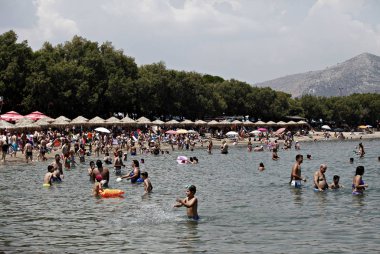 İnsanlar Temmuz ayında Atina Yunanistan 'ın kuzeydoğu banliyölerinde plajları güneşli hava tadını çıkarın. 26, 2015.