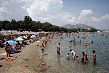 İnsanlar Temmuz ayında Atina Yunanistan 'ın kuzeydoğu banliyölerinde plajları güneşli hava tadını çıkarın. 26, 2015.