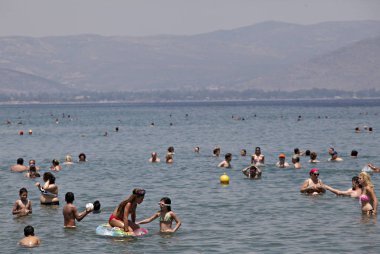 İnsanlar Temmuz ayında Atina Yunanistan 'ın kuzeydoğu banliyölerinde plajları güneşli hava tadını çıkarın. 26, 2015.