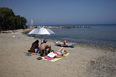 İnsanlar Temmuz ayında Atina Yunanistan 'ın kuzeydoğu banliyölerinde plajları güneşli hava tadını çıkarın. 26, 2015.