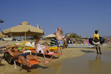 Bir sokak satıcısı Naxos, Yunanistan Agios Prokopios köyünün plajında güneş gözlüğü satıyor 19 Ağustos 2018