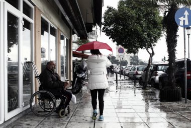 Yayalar Selanik'te bir yağış sırasında şemsiye ile yağmurdan kendilerini korumak, Nisan 28, 2014