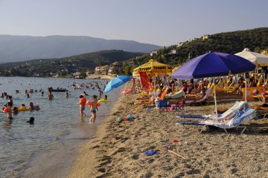 İnsanlar 6 Ağustos 2018'de Yunanistan'ın Afissos köyü sahilinde denizde yüzerken güneşli havanın tadını çıkarıyorlar.