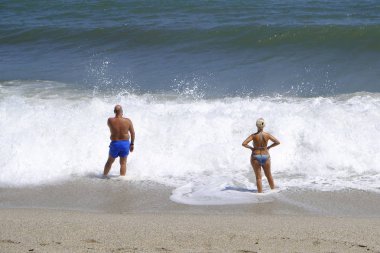İnsanlar 10 Ağustos 2018'de Yunanistan'ın Agios Ioannis köyü sahilinde denizde yüzerken güneşli havanın tadını çıkarıyorlar.