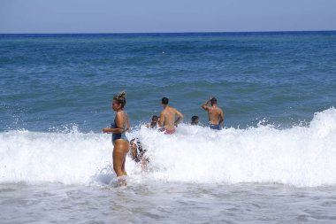 İnsanlar 10 Ağustos 2018'de Yunanistan'ın Agios Ioannis köyü sahilinde denizde yüzerken güneşli havanın tadını çıkarıyorlar.