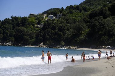İnsanlar 10 Ağustos 2018'de Yunanistan'ın Agios Ioannis köyü sahilinde denizde yüzerken güneşli havanın tadını çıkarıyorlar.