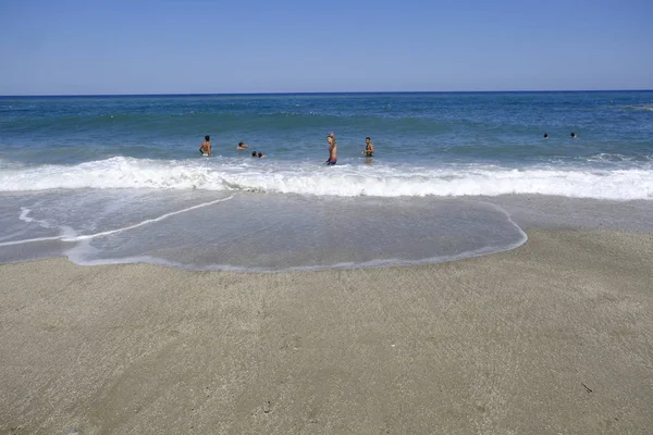 İnsanlar 10 Ağustos 2018'de Yunanistan'ın Agios Ioannis köyü sahilinde denizde yüzerken güneşli havanın tadını çıkarıyorlar.