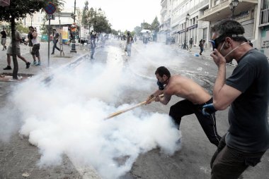 Polis ve göstericiler 28 Haziran 2011 tarihinde Atina'da hükümetin politikası ve kemer sıkma kesintilerine karşı 48 saatlik bir genel grev sırasında Yunan parlamentosu önünde çatışma