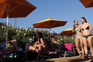 İnsanlar Agia Marina sahilde güneşli havakeyfini, Yunanistan, Jul. 15, 2012.